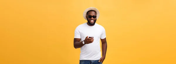 携帯電話アプリケーションを使用して白いシャツで陽気なアフリカ系アメリカ人 携帯電話でソーシャル ネットワークからニュースを読む幸せな暗い皮を剥がれた流行に敏感な男 — ストック写真