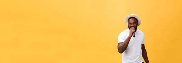 感情的なモーション ジェスチャーで 黄色の背景に分離されたマイクを使って歌っているハンサムなアフリカ系アメリカ人少年 — ストック写真
