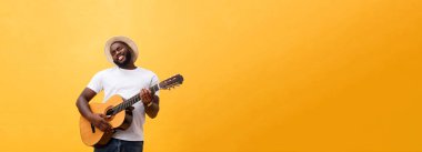 Kot pantolon ve beyaz kolsuz bluz giyen gitar, çalmak kas siyah adam. Sarı arka plan üzerinde izole
