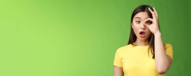 Şaşırtıcı dilsiz, tatlı Asyalı genç kız, çeneni indir, şaşırt, çember işaretine bak, çeneni indir, nutkun tutulsun, etkileyici kamera, inanılmaz tanıtıma bak, yeşil arka planda dur.