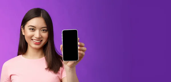 特写漂亮可爱的女店员赠送新的手机应用程序 手持智能手机显示电话屏幕 介绍应用程序 站在紫色背景上高兴 — 图库照片