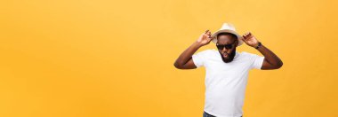 Holding şapkası izole sarı arka plan üzerinde el ile gülen genç bir adam portresi kapatın.