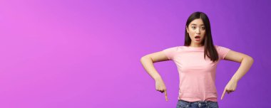 Şaşırmış tatlı Asyalı şaşırmış kız, titremiş çene hayal kırıklığına uğramış, soluk soluğa kalmış, şaşırmış, alt reklamlara işaret eden, olumsuz görüş, mor arka plan.