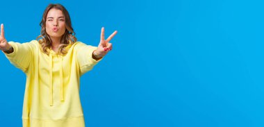 Güzel, aptal, güzel bir genç kız, olumlu titreşimler gönderir, barış jestleri gösterir, göz kırpar ve hava öpücüğü verir, dudakları kıvrılmış, eğlenir, eğlenir, eğlenir, güzel bir parti verir, mavi arka planda durur..