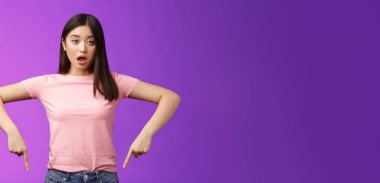 Şaşırmış tatlı Asyalı şaşırmış kız, titremiş çene hayal kırıklığına uğramış, soluk soluğa kalmış, şaşırmış, alt reklamlara işaret eden, olumsuz görüş, mor arka plan.