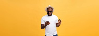 Cep telefonu ve take away kahve fincanı ile yakışıklı Afrikalı-Amerikalı. Sarı altın arka plan üzerinde izole