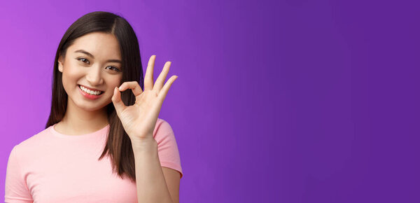 Cute smiling asian girl approve good plan, show okay ok sign, tilt head lovely grinning, satisfied perfect quality product, give positive feedback, accept choice, stand purple background.