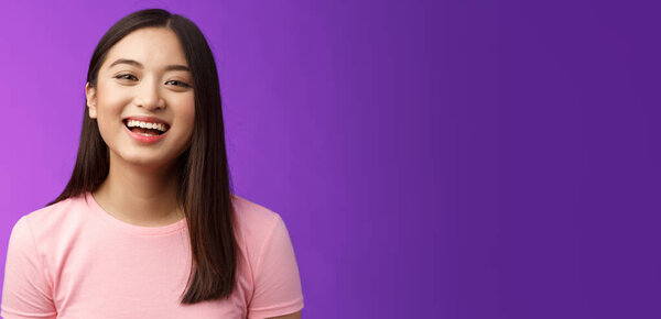 Close-up lively carefree cheerful asian girl laughing, having fun, smiling amused enjoy friendly relaxing conversation, stand purple backgrond joyful, look camera upbeat. Copy space