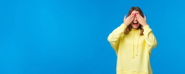 Arkadaşlarını bekleyen kız ellerini açıp 10 'a kadar say doğum günü partisinde, kız arkadaş sürpriz hediyeler getiriyor, heyecanla gülümsüyor, cee oynuyor, mavi arka planda duruyor..