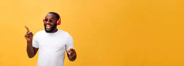 若いアフリカ系アメリカ人の男は身に着けているヘッドフォンとイエローゴールドで音楽を楽しむ背景 — ストック写真