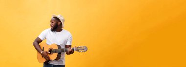 Kot pantolon ve beyaz kolsuz bluz giyen gitar, çalmak kas siyah adam. Sarı arka plan üzerinde izole