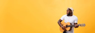 Kot pantolon ve beyaz kolsuz bluz giyen gitar, çalmak kas siyah adam. Sarı arka plan üzerinde izole