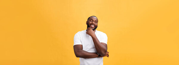 Portrait of a modern young black man smiling with arms crossed on isolated yellow background.