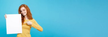 Boş işaret gösteren gülümseyen portre genç güzel çekici Kızıl kızıl saçlı kız kadar yakın. Mavi Pastel renkli. Kopya alanı