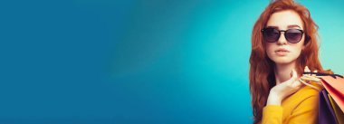 Alışveriş kavramı - portre genç güzel çekici Dişileştirilmiş kız kameraya alışveriş çantası ile seyir gülümseyen yakından. Mavi Pastel renkli. Kopya alanı.