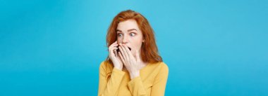 Yaşam tarzı kavramı - Kızıl kızıl saçlı kız arkadaşı ile cep telefonuyla konuşurken şok edici ve stresli ifade ile portresi. Pastel mavi arka plan üzerinde izole. Kopya alanı