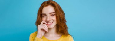 Kameraya gülümseyen kızıl saçlı mutlu kızıl saçlı kızın portresi. Pastel mavi arka plan. Boşluğu Kopyala.