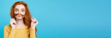 Headshot saç sahte bıyıklı adam olmak taklit mutlu Kızıl kızıl saçlı kız portresi. Pastel mavi arka plan. Kopya alanı.