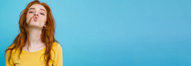 Komik surat kameraya bakarak mutlu Kızıl kızıl saçlı kızla headshot portresi. Pastel mavi arka plan. Kopya alanı.