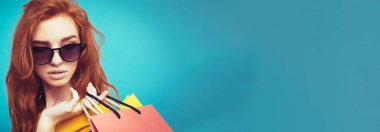 Alışveriş kavramı - portre genç güzel çekici Dişileştirilmiş kız kameraya alışveriş çantası ile seyir gülümseyen yakından. Mavi Pastel renkli. Kopya alanı.