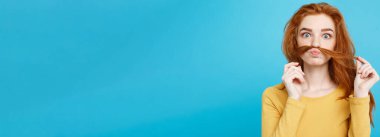 Headshot saç sahte bıyıklı adam olmak taklit mutlu Kızıl kızıl saçlı kız portresi. Pastel mavi arka plan. Kopya alanı.