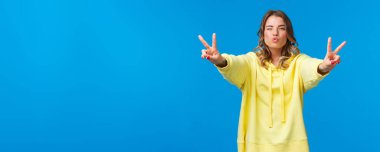 Güzel, aptal, güzel bir genç kız, olumlu titreşimler gönderir, barış jestleri gösterir, göz kırpar ve hava öpücüğü verir, dudakları kıvrılmış, eğlenir, eğlenir, eğlenir, güzel bir parti verir, mavi arka planda durur..