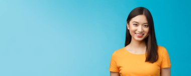 Yakın plan çekici Asyalı kız saf cilt hastalığı, neşe içinde gülümsüyor kameraya iyimser bak, kibarca dinle, olumlu motivasyonunu dile getir başarı elde et, mavi arka planda dur..