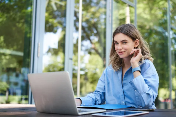 Portrait of business woman working on fresh air. Corporate female with laptop, sitting outside office building and using computer.