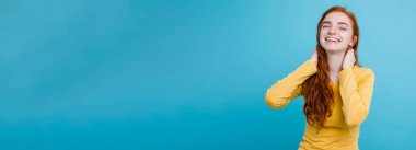 Kameraya bakarak gülen çiller ile mutlu Kızıl kızıl saçlı kız portresi. Pastel mavi arka plan. Kopya alanı.