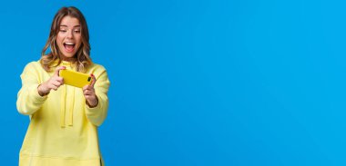 Kız yarış oyununda seviye geçmek için akıllı telefonu yana çeviriyor, boş zamanlarında cep telefonu kullanıyor, güzel yeni uygulamalar indiriyor, cep telefonunu yatay olarak tutuyor, gülüyor.
