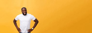 Gülümseyen izole sarı zemin üzerinde duran modern genç bir siyah adam portresi.