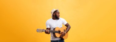 Kot pantolon ve beyaz kolsuz bluz giyen gitar, çalmak kas siyah adam. Sarı arka plan üzerinde izole