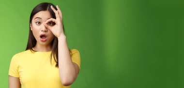 Şaşırtıcı dilsiz, tatlı Asyalı genç kız, çeneni indir, şaşırt, çember işaretine bak, çeneni indir, nutkun tutulsun, etkileyici kamera, inanılmaz tanıtıma bak, yeşil arka planda dur.