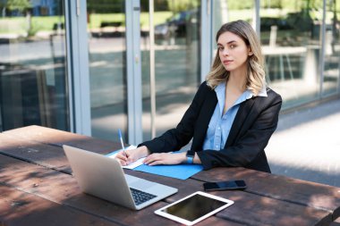 Açık havada çalışan başarılı bir iş kadını. Şirket kadını dizüstü bilgisayarla bankta oturuyor, yazıyor, iş toplantısı sırasında notlar alıyor..