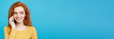 Yaşam tarzı ve teknoloji kavramı - eğlenceli ve heyecan verici arkadaşla cep telefonuyla konuşurken ile neşeli mutlu Kızıl kızıl saçlı kız portresi. Pastel mavi arka plan üzerinde izole. Kopya alanı