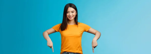 陽気な自己アジアの女の子の暗いHaitcutは黄色の夏のTシャツを着用プロモーションを導入し 手を指して 下の広告笑顔を示す 喜んで良いリンク青の背景を共有 — ストック写真
