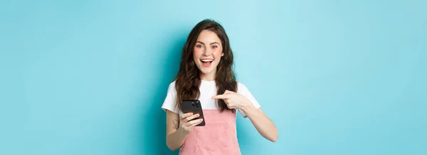 Retrato Bonito Alegre Menina Apontando Dedo Para Telefone Usando Aplicativo — Fotografia de Stock