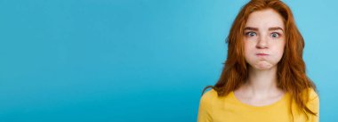 Komik surat kameraya bakarak mutlu Kızıl kızıl saçlı kızla headshot portresi. Pastel mavi arka plan. Kopya alanı.