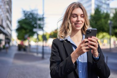 Gülümseyen genç bir satıcının portresi, iş kadını cep telefonuna mutlu bir yüzle bakıyor, akıllı telefondan mesaj okuyor..