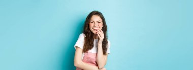 Gülen ve eğlenen, beyaz dişleriyle gülümseyen, komik filmden hoşlanan, mavi arka planda duran mutlu ve çekici bir kadının portresi..