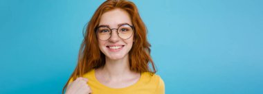 Kameraya gülümseyen kızıl saçlı mutlu kızıl saçlı kızın portresi. Pastel mavi arka plan. Boşluğu Kopyala.