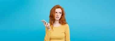 Yaşam tarzı kavramı - cep telefonu üzerinde konuşurken sarı elbiseli kız portresi bir şok şaşırttı. Pastel mavi arka plan üzerinde izole. Kopya alanı.