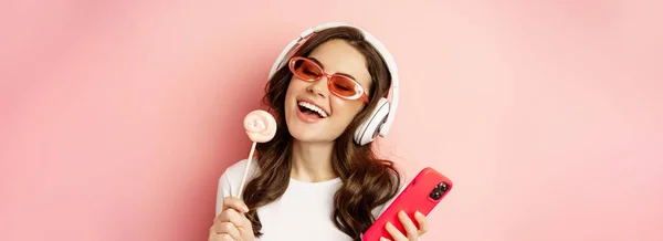 Beautiful Female Model Listening Music Headphones Holding Lolipop Mobile Phone — Foto Stock