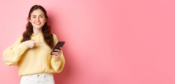 Изображение Счастливой Улыбающейся Молодой Женщины Держащей Мобильный Телефон Указывающей Мобильный — стоковое фото