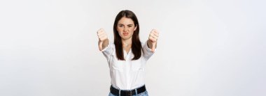 Disappointed adult corporate woman showing thubms down, dislike gesture, negative feedback, complaining and grimacing, white background.