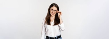 Portrait of female office worker, businesswoman looking at camera and smiling, standing over white background. Copy space
