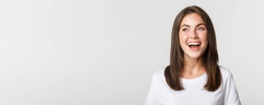 Sol üst köşeye bakıp gülen neşeli, güzel esmer kızın yakın plan fotoğrafı..