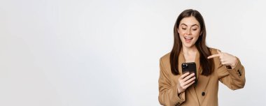 Hevesli satıcı, iş kadını cep telefonunu işaret eden ve gülümseyen, cep telefonuyla konuşan, beyaz arka planda duran..