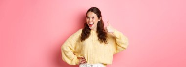 Güzel esmer kadın modelin portresi, sizin fikriniz gibi, destekleyin, onaylayın ya da övün, pembe arka planda duran güzel bir şeyi..