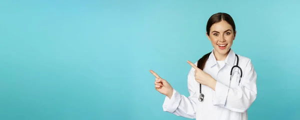 Portrait Smiling Medical Worker Girl Doctor White Coat Stethoscope Pointing — Zdjęcie stockowe